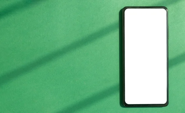 Zelené pozadí s mobilním telefonem vztyčit. Bílá obrazovka smartphonu na eko banneru — Stock fotografie