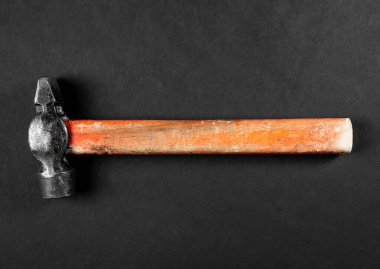 Siyah arka planda metal kafası ve tahta sapı olan eski model bir çekiç.