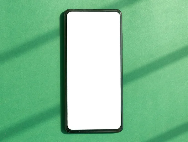 휴대 전화는 낮에 녹색 배경의 템플릿을 흉내낸다. 스마트폰의 흰색 화면의 상단 사진 — 스톡 사진