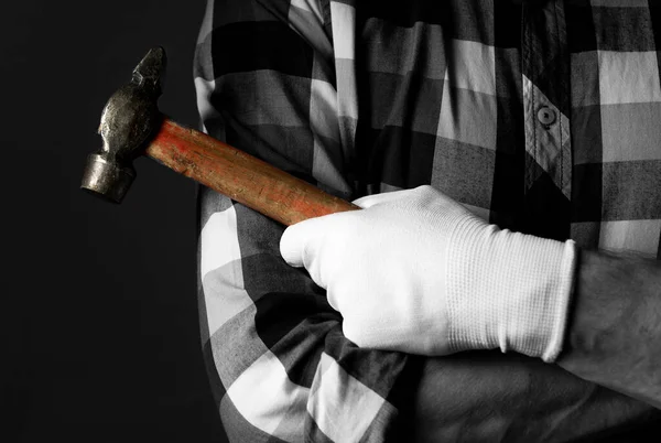 Reparaturhelfer Hand in Hand mit Handschuhen halten das Hammer-Werkzeug in der Nähe. Negatives Schwarz-Weiß-Foto — Stockfoto