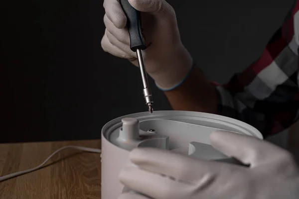 Repairing humidifier with screw driver. Screwdriver tool in hands of repairman