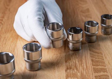 Erkek eli ve çizgisi metal çeliğin uğursuz yuvaları veya ahşap masanın üzerindeki altıgen metal başlıklar