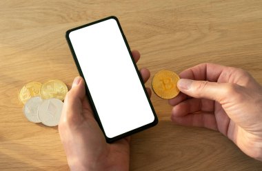 Erkek eller cep telefonunu sahte ekran için tutarken bitcoin para da ahşap masanın üzerinde.