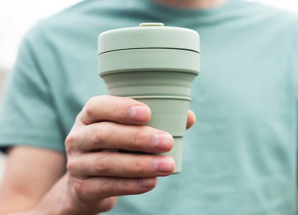 Eko kubek wielokrotnego użytku do kawy na wynos. Mężczyzna ręka z trwałym kubek silikonowej herbaty. Osoba przyjazna dla środowiska — Zdjęcie stockowe