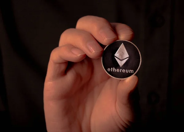 Ethereum ezüst crypto érme férfi kezében fekete háttér. Eth vagy éterum — Stock Fotó