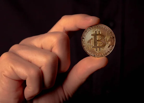 Glänsande bitcoin BTC gyllene mynt i manlig hand över svart bakgrund. Bit kryptovaluta — Stockfoto