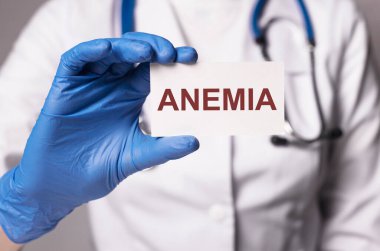 Anemi yazılı kağıt üzerinde doktor eli mavi eldivenli yakın plan.