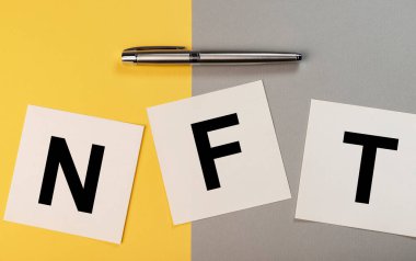 Sarı ve gri arkaplan üzerine kağıt notlarda NFT kısaltması