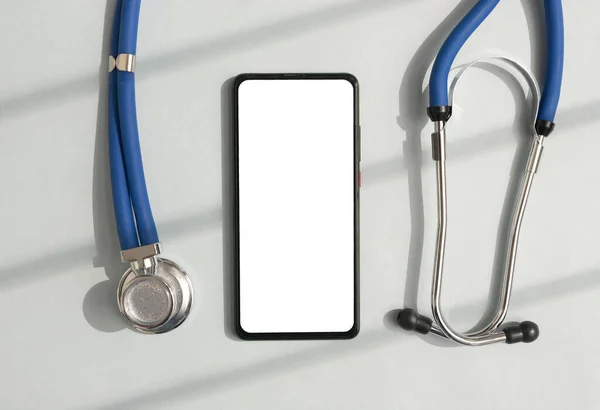 Cep telefonu sağlık uygulaması için modelleme yapıyor. Çevrimiçi sağlık uygulaması için akıllı telefon beyaz ekran maketi ve steteskop
