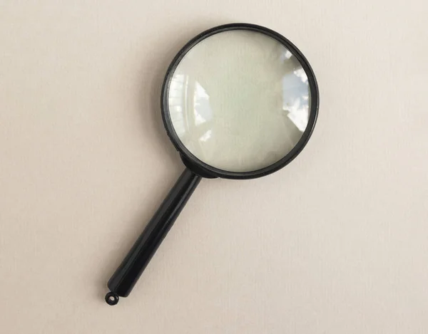 Magnifying glass over pale beige background. Magnifier as concept of finding answers — Stock Photo, Image