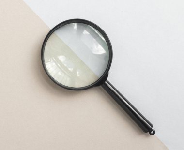 Soluk mavi ve bej arka planda büyüteç. Büyüteç kavramı