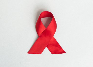 AIDS ve HIV günü farkındalığı için kırmızı kurdele. Mavi arkaplanda kıvrımlı saten fiyonk