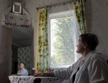 Kırsal kesimde yaşayan bir kadın dini İsa ikonuna bakıp dua ediyor. Gerçek insanların fotoğrafı..