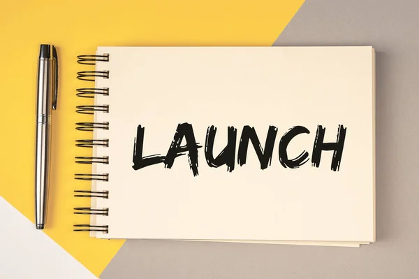 Launch word on notepad paper on yellow and grey background.