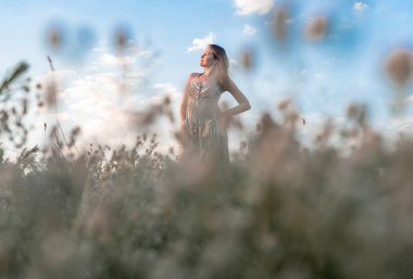 Young blissed woman with in summer field enjoying freedom and summer holidays