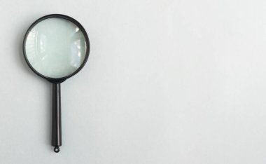 Magnifying lens over pale blue gray background with place for text. Banner with magnifier