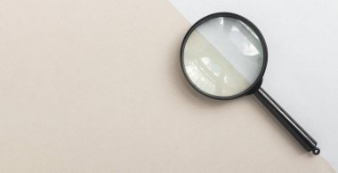 Magnifying glass or loupe on pale blue and beige background. Magnifier banner with copy space