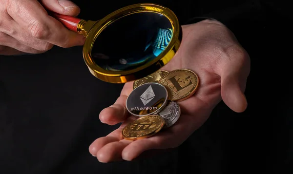 Ethereum, silver and golden coins of cryptocurrency in male hand palm over black background, close up — Stockfoto