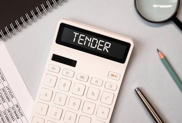 Word tender on calculator on office desk with stationery, top view — Stock Photo, Image