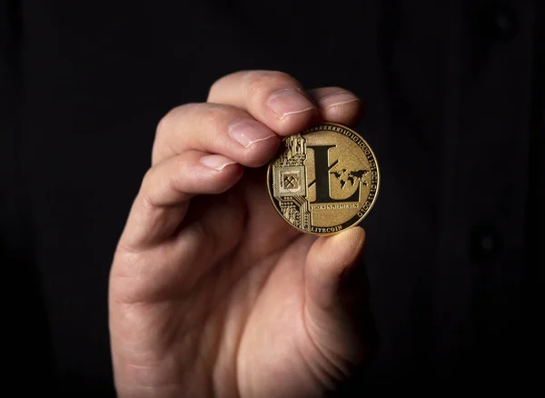 Litecoin gyllene mynt i manlig hand över svart bakgrund — Stockfoto