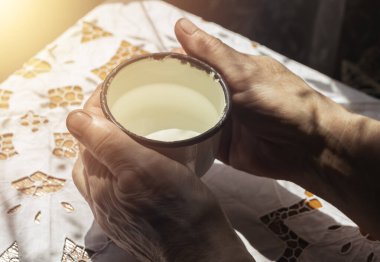 Çiftlik işlerinden sonra kirli kadın elleri suyla birlikte metal beyaz kupa alıyor. Susamış çiftçi konsepti