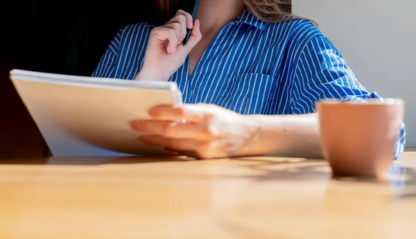 Women hands close up holding notepad, reading syllabus in coffee shop with coffee cup on wooden table. Copy space for text available — Stockfoto