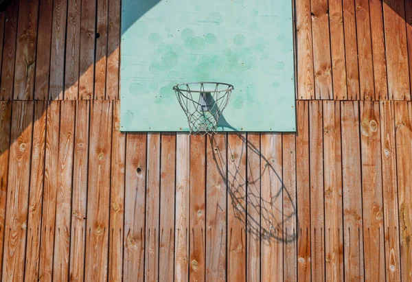 Basketbalový koš na dřevěné stěně domu se sítí na hraní, sluneční světlo a stín — Stock fotografie