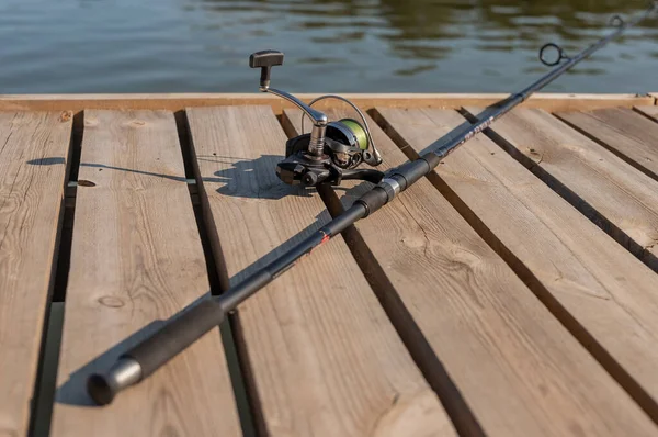 夏に川や湖の上の木製の海岸に横たわっている釣竿や釣り竿を閉じる — ストック写真