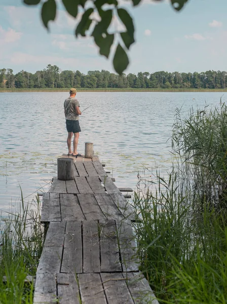 Pescatore di nuovo sul vecchio molo di legno sopra l'acqua del lago in estate — Foto Stock