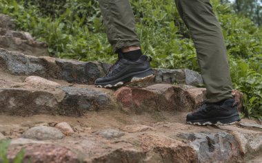 Erkek bacakları spor ayakkabıların içinde, doğada merdivenleri tırmanıyor.