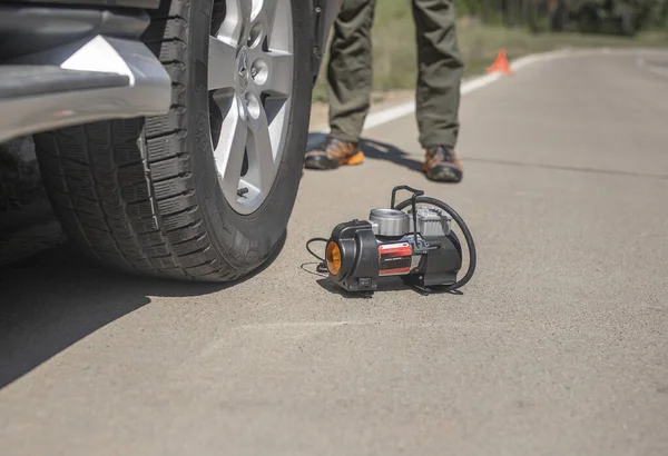 Φορητή αντλία ελαστικών για φουσκωτή ρόδα αυτοκινήτου στο δρόμο. Φουσκωτής ελαστικών αεροσυμπιεστής με μανόμετρο — Φωτογραφία Αρχείου