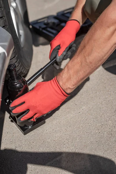 Hydraulick γρύλος τίθεται κάτω από το αυτοκίνητο με αρσενικά χέρια — Φωτογραφία Αρχείου
