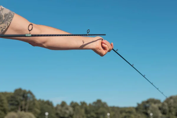 Mannelijke handen houden gebroken hengel vast en monteren deze in de zomer boven de blauwe heldere lucht — Stockfoto