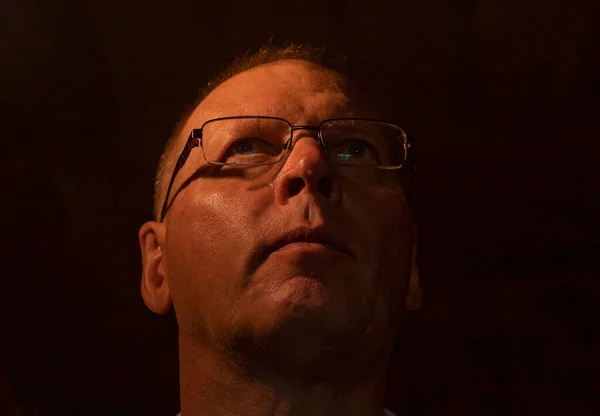 Een volwassen man met een bril die opkijkt naar licht vanuit de lucht. Spiritueel inzicht concept — Stockfoto