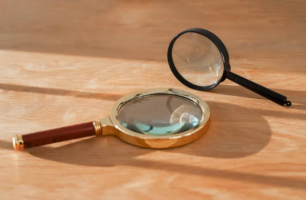 Two magnifying glasses on wood desk with daylight. Concept of observation, exploration, study and research — Stock Photo, Image