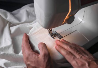 Erkek eller dikiş makinesinde tekstil işliyor. Elle terzilik