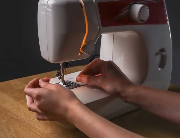 Seamstress mãos inserção de linha através do furo da agulha na máquina de costura, começando o trabalho — Fotografia de Stock
