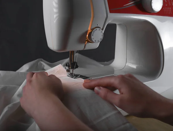 Женские руки за швейной машинкой во время рабочего процесса с тканью — стоковое фото
