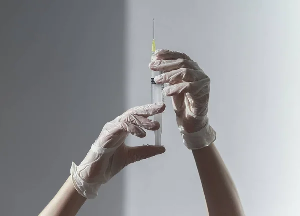 Jeringa con aguja en las manos de los médicos con guantes blancos — Foto de Stock