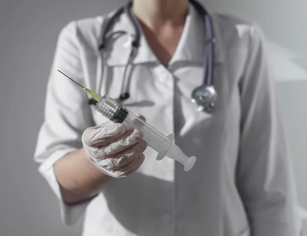 Plastikspritze mit scharfer Nadel und Flüssigkeit in den Händen von Ärzten oder Krankenschwestern, die sie in Richtung Kamera gibt — Stockfoto