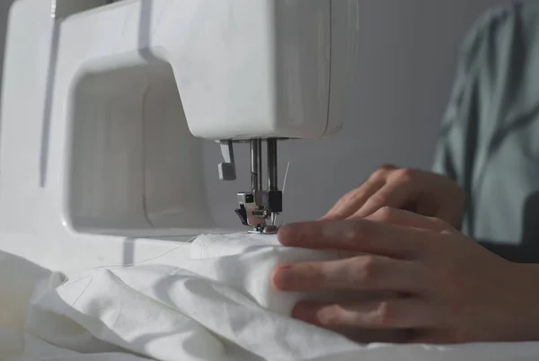 Руки швеи с льняной тканью на швейной машинке, рабочий процесс с натуральным хлопковым текстилем — стоковое фото