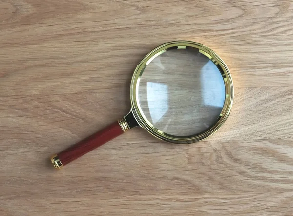 Magnifying glass on wooden desk as symbol of research and study — Stock Photo, Image