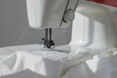 Dikiş makinesinin üzerindeki beyaz pamuk kumaşı kapat.