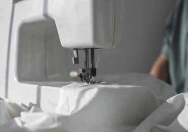 Dikiş makinesinin üzerindeki beyaz pamuk kumaşı kapat.