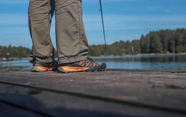 Gambe di pescatori su pontile o pontile di legno durante la pesca — Foto Stock