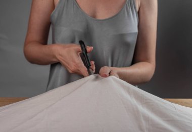 Eller, dikiş makası ile kumaşı keserek kapatır.