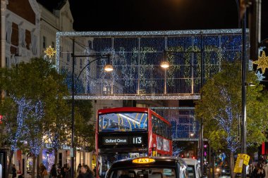 Londra, İngiltere - 3 Kasım 2020: Oxford Caddesi, Londra 'da Noel ışıkları, yeni İngiltere ulusal tecrit başlamadan hemen önce, ön planda kırmızı bir Londra çift katlı otobüs ve taksiyle