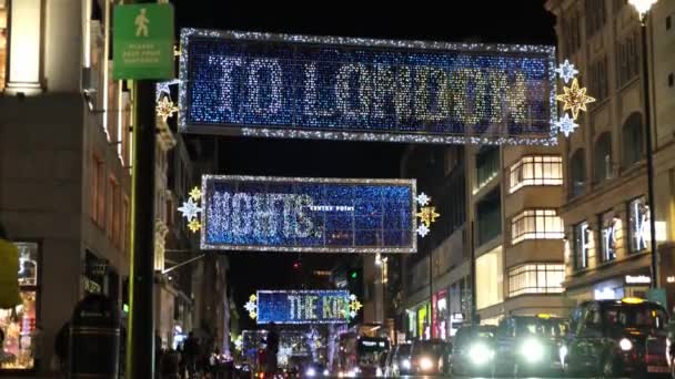英国伦敦 2020年11月3日 牛津街圣诞彩灯沿线的低视野 马路对面有一排黑色出租车 尽头有一个骑自行车的人从路标下经过 — 图库视频影像