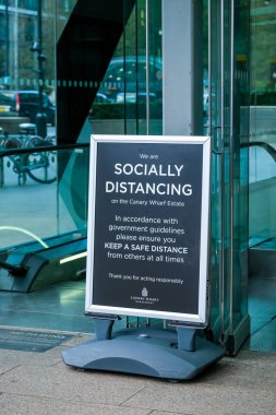 Londra, İngiltere - 4 Kasım 2020: Canary Wharf 'ta insanlardan COVID-19' un yayılmasını önlemek için sosyal uzaklık kurallarına uymalarını isteyen bir tabela