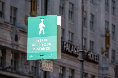Londra, İngiltere - 1 Haziran 2021: Arka planda binalar bulunan bir sokak lambası üzerinde insanlardan mesafelerini korumalarını isteyen bir tabela